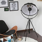 Black tripod floor lamp with circular reflective shade on three legs