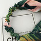 Green and pink leaf-pattern turban headband worn across the forehead
