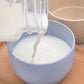 Blue wheat straw coffee cup with handle, milk being poured into cup.