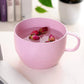 Pink wheat straw coffee cup with handle, filled with rose buds.