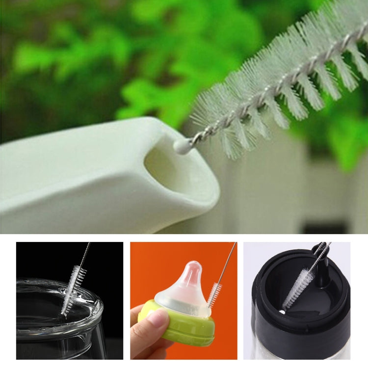 Straw cleaning brush with white bristles and metal wire, shown near drink cup