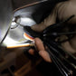 Close-up mini LED keychain flashlight lighting a metal surface, bronze frame, black head