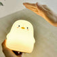 Soft yellow penguin-shaped silicone night light held in hands.