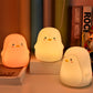 Set of three glowing penguin-shaped silicone night lights on display shelf.