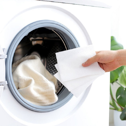 Hand placing a white laundry color absorption film sheet into washer drum