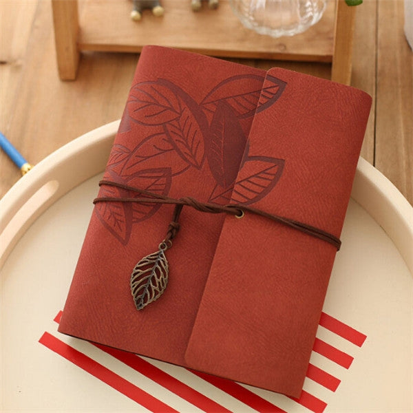 Maroon photo album cover with leaf embossing, twine tie, and hanging leaf charm.