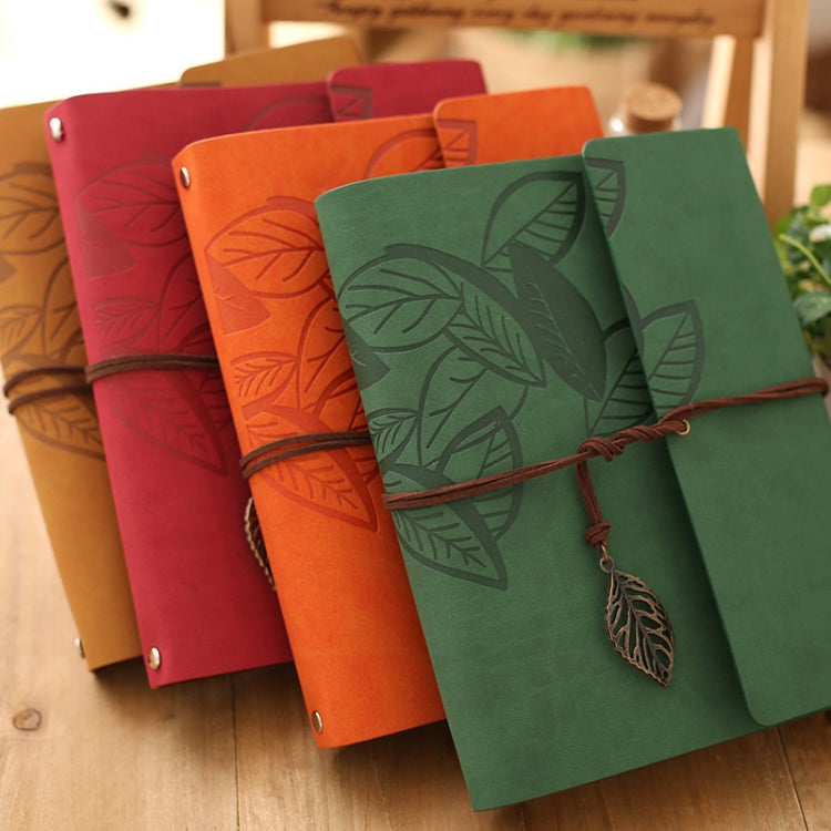 Stacked vintage photo albums in red, orange, and green with leaf embossing and ties.