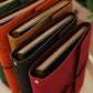 Assorted color PU leather photo albums with bound spines, leaf embossing, and tied straps.
