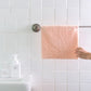 Pink microfiber face towel on a bathroom towel bar, held up by hand