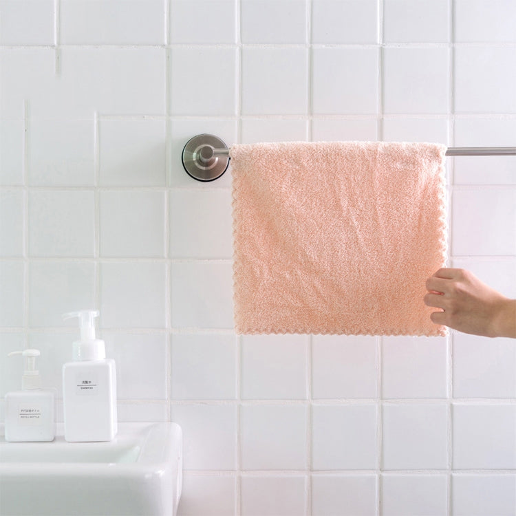 Pink microfiber face towel on a bathroom towel bar, held up by hand
