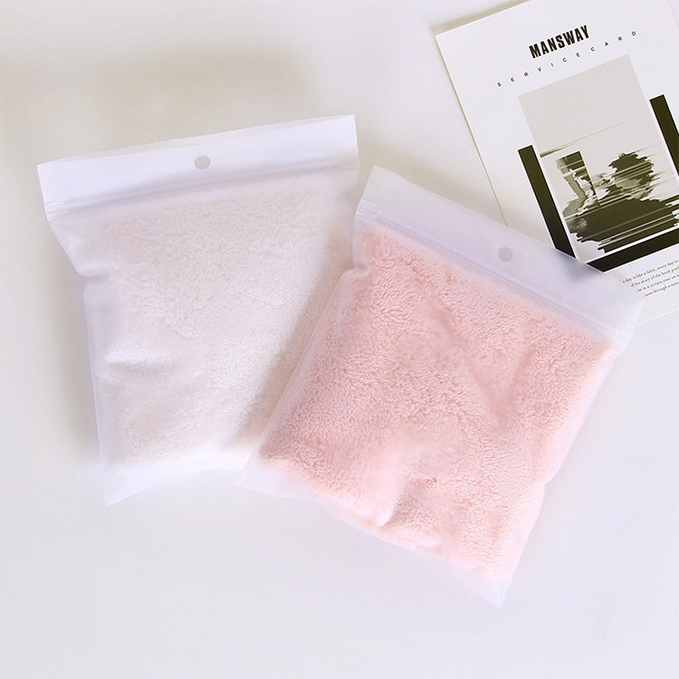 Pink microfiber face towel sealed in a clear plastic bag with white towel behind