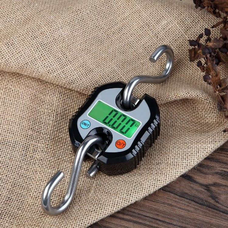 Orange mini digital hook scale with green LCD and two metal hooks on a surface