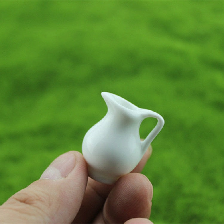 Mini white ceramic vase with curved spout and small handle opening, held in hand