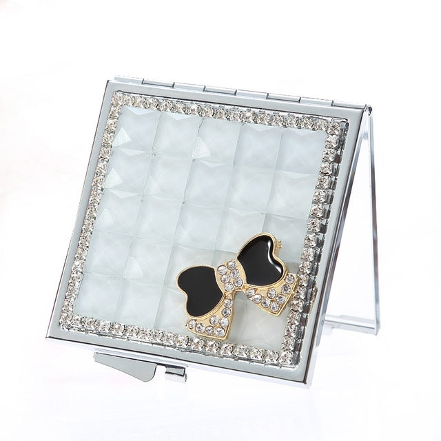 Open mini compact mirror with silver rhinestone frame, light mirror panel, and bow charm