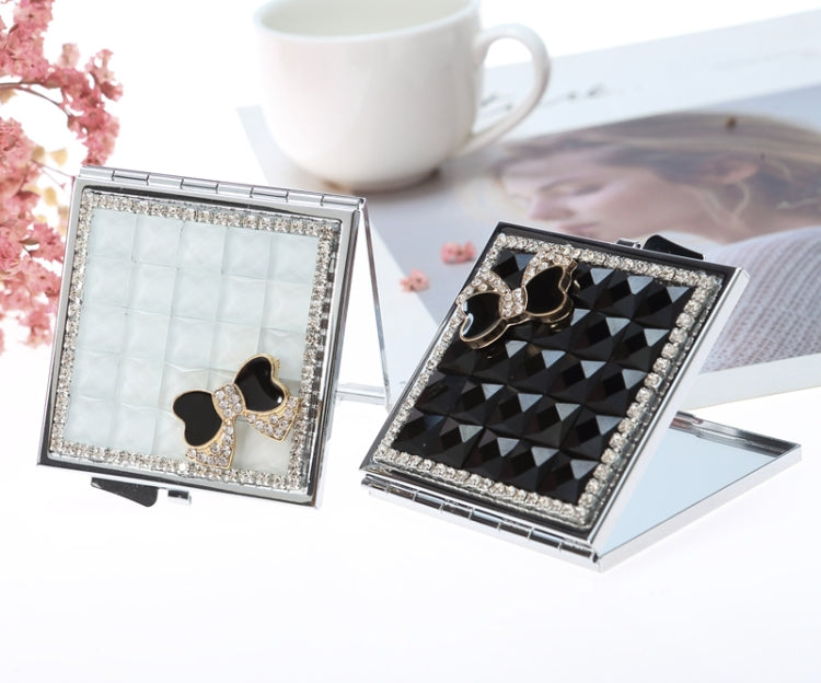 Mini folding mirror compact showing light and dark mirror panels with gem bow accents