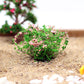 Artificial handmade model flower bush with green leaves and pink blossoms