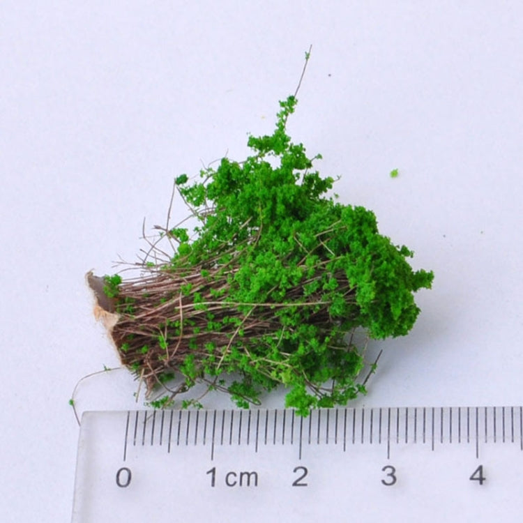 Artificial handmade model flower bush with green foliage next to a small ruler scale