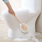 Handheld sponge brush scrubbing a toilet rim with pink circular pad