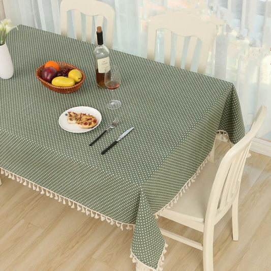 Green cotton tablecloth with white dots and scalloped-style tassel fringe at the edges