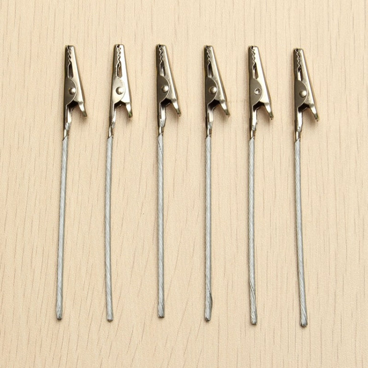 Set of metal wire rope alligator clips with silver jaws on wood surface