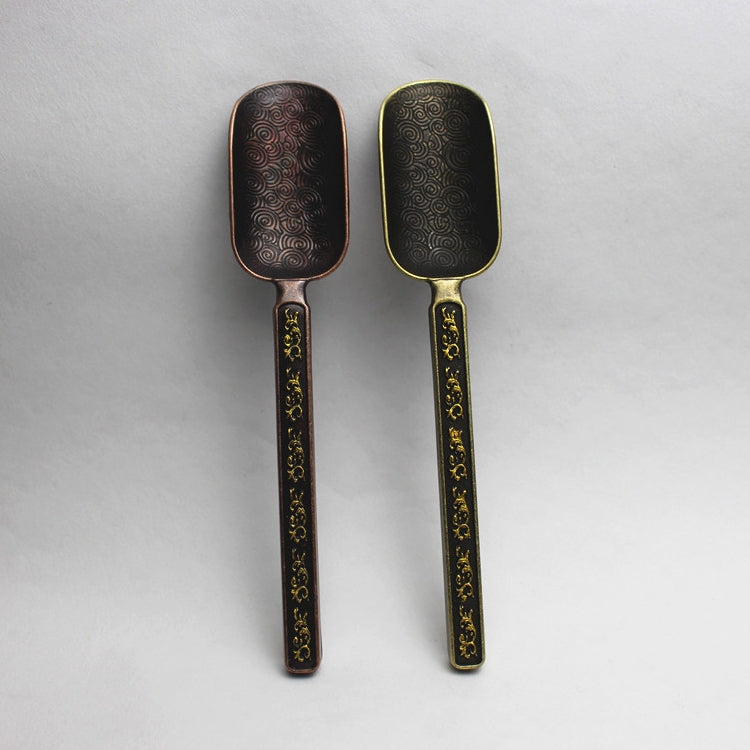 Pair of dark metal tea spoons with gold filigree handles and swirl bowls
