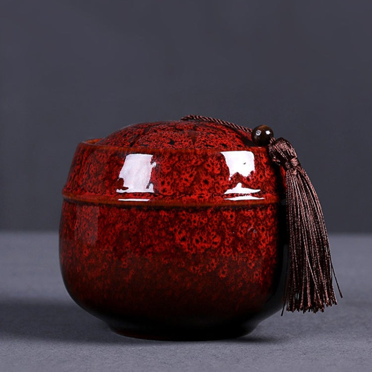 Red ceramic mini tea storage can with glossy lid and hanging tassel pull cord.