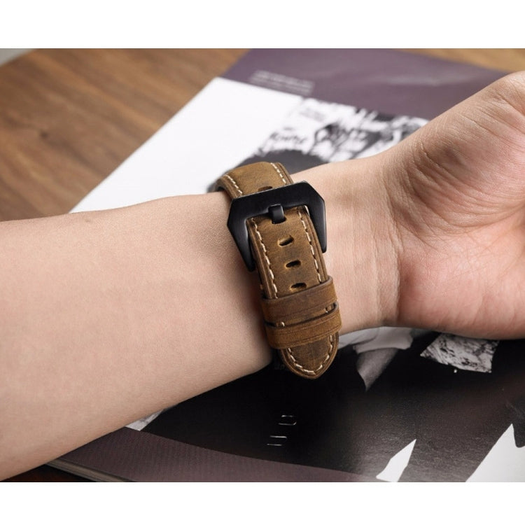 Brown leather watch band on wrist with black buckle and punched holes