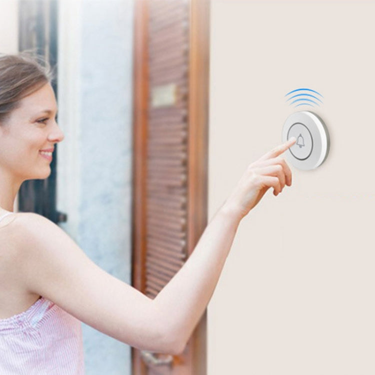 Person pressing a round white wireless doorbell button with bell icon