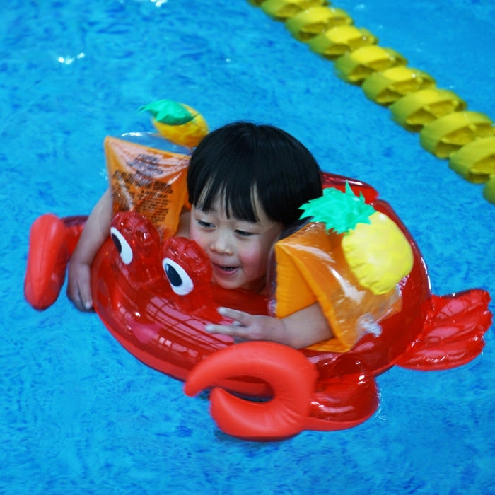Child wearing a yellow pineapple-shaped inflatable arm band with green spiky top