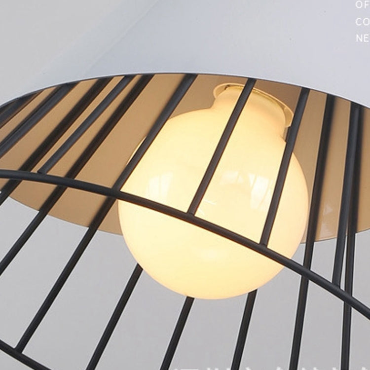 Close-up of white bulb inside black metal cage pendant light with wood top.