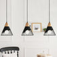 Set of three pendant lights with wood tops and black metal cage shades on cords.
