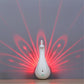 Peacock-shaped LED night light glowing with red light rays behind it