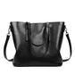 Black PU shoulder bag with curved front panel, drawstring-style pull tab, and side straps