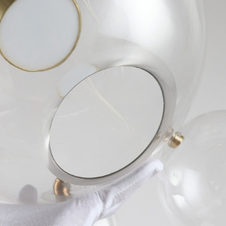 Clear glass globe lamp detail with gold socket hardware and metal mounting ring