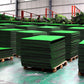 Stacked portable indoor golf practice mats on wooden pallets, green turf visible