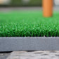Close-up of green turf golf practice mat seam with dark foam backing