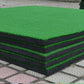 Square golf practice mat with green turf top and dark layered foam sides