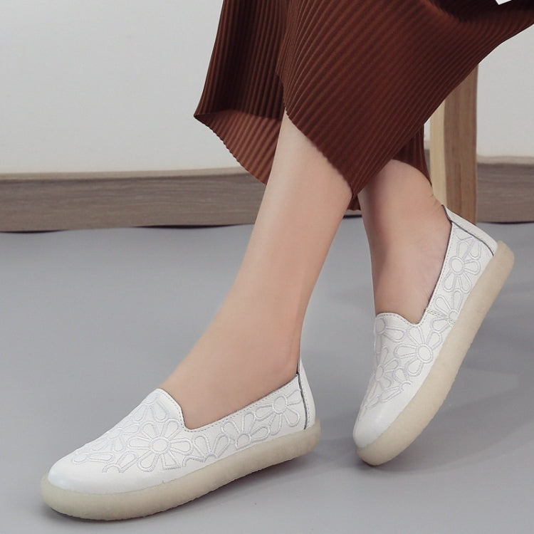 White embroidered slip-on casual shoes featuring floral cutout-style stitching and low sole
