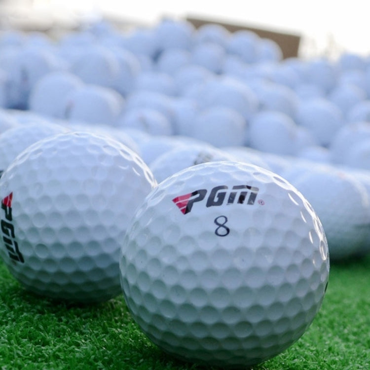 Three-layer white golf balls with PGM logo and “8” marking on grass