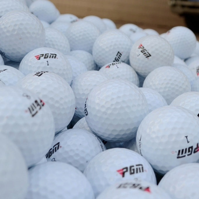 Assorted white PGM golf balls with dimpled texture and printed logos