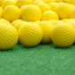 Yellow indoor golf rubber balls on turf, close grouped view