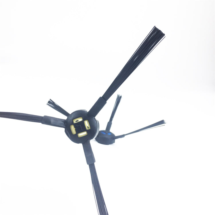 Close-up view of two robotic vacuum side brushes with dark bristles and yellow lock clips